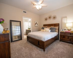 Little Rock apartment for rent - A bedroom with a large bed, a dresser, and a ceiling fan.