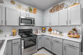 Norman townhouse for rent - A kitchen with white cabinets and a black stove top.
