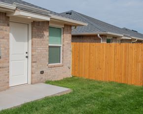 Oklahoma City triplex for rent - A house with a white door and a wooden fence.