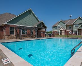 Oklahoma City apartment for rent - A swimming pool in front of a house with a sign on the ground.