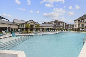 Owasso townhouse for rent - A large swimming pool in front of a building with a fence around it.