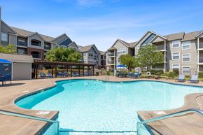 Edmond apartment for rent - A large swimming pool in front of apartment buildings.