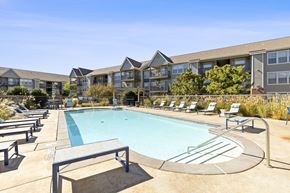 Amarillo apartment for rent - A swimming pool surrounded by sun loungers and chairs in front of apartment buildings.