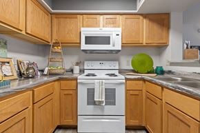 Oklahoma City apartment for rent - A kitchen with a white stove and wooden cabinets.