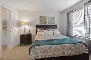 Oklahoma City apartment for rent - A bedroom with a large bed and a lamp on a side table.