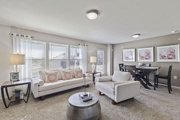 Lubbock apartment for rent - A living room with a white couch, a grey armchair, a coffee table, and a dining table with chairs.