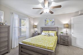 Lubbock apartment for rent - A bedroom with a bed, dresser, and ceiling fan.