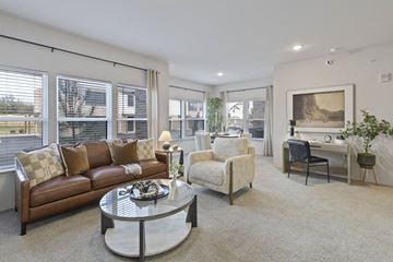 Kansas City townhouse for rent - A living room with a brown leather couch, a white chair, and a glass coffee table.