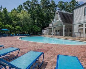Ridgeland apartment for rent - A pool surrounded by blue lounge chairs and a house in the background.