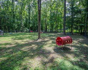 Ridgeland apartment for rent - A red barrel sits in the middle of a grassy area with trees in the background.