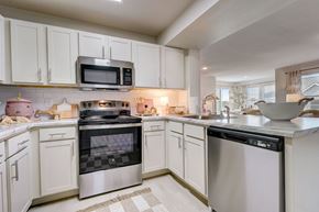 Yukon townhouse for rent - a kitchen with white cabinets and stainless steel appliances