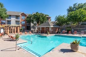 El Paso apartment for rent - A swimming pool surrounded by chairs and a small building.
