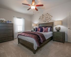 Oklahoma City apartment for rent - A bedroom with a large bed and a ceiling fan.