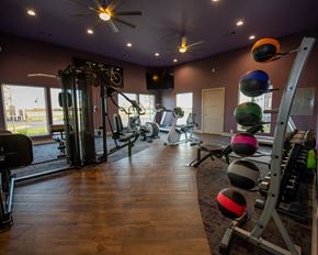 Oklahoma City apartment for rent - A gym with a variety of equipment including a weight rack, a rowing machine, and a wall mounted pull up bar.