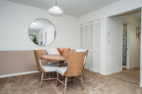 Ridgeland apartment for rent - A dining room with a round mirror, wooden chairs, and a table with a white tablecloth and a vase of flowers.