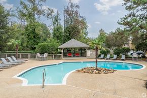 Ridgeland apartment for rent - A pool surrounded by trees and chairs.
