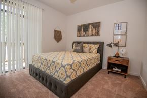 Ridgeland apartment for rent - A bedroom with a large bed and a small table with a clock on it.