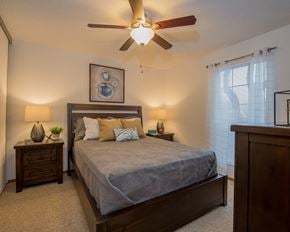 Oklahoma City apartment for rent - A bedroom with a bed, nightstands, and a ceiling fan.