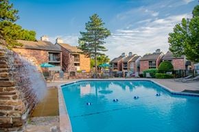 Oklahoma City apartment for rent - A pool with a waterfall and a building in the background.