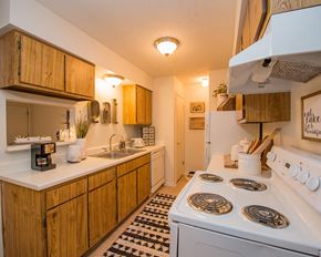 Oklahoma City apartment for rent - A kitchen with a white stove and wooden cabinets.