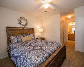 Oklahoma City apartment for rent - A bedroom with a bed, a ceiling fan, and a wreath on the wall.
