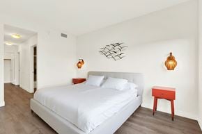 Los Angeles apartment for rent - A bedroom with a white bed and a red stool at Twelve One Ten Rochester, California 90025