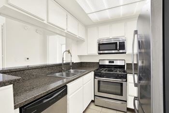 A kitchen with a black countertop and stainless steel appliances