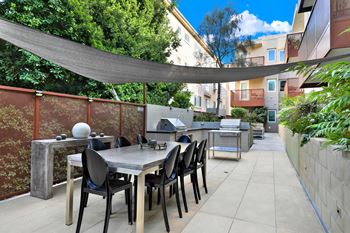 A patio with a table and chairs under a shade sail