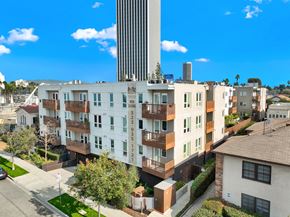 Los Angeles apartment for rent - A tall building with a white facade stands in front of a row of houses at The Urbanpolitan, Los Angeles, California