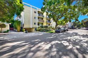 Los Angeles apartment for rent - A car is parked on the street in front of a yellow building at Wooster Encore Apartments, Los Angeles, CA