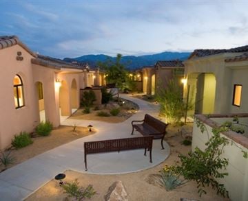 Palm Desert apartment for rent - A courtyard with a bench and a wall with windows.