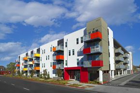 San Ysidro apartment for rent - A modern multi-story apartment building with balconies and a mix of red, yellow, and white colors.