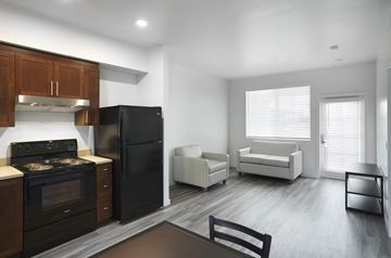 Buena Park apartment for rent - A black refrigerator sits in a kitchen with wooden cabinets and a stove.