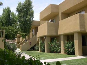 Palm Desert apartment for rent - A building with a beige facade and a green lawn in front.