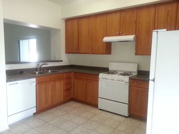Indio apartment for rent - an empty kitchen with white appliances and wooden cabinets