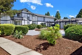 Kent apartment for rent - A white building with a black roof and a green bush in front.