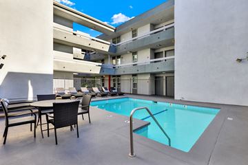 Los Angeles apartment for rent - A pool area with chairs and a table is surrounded by apartment buildings.