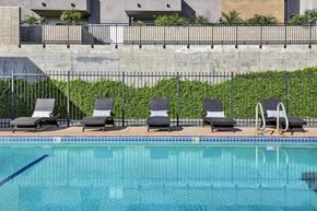 Van Nuys apartment for rent - A pool with chairs and a wall of green plants at Sylvan Gardens,Van Nuys,California