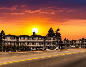 Kent apartment for rent - A sunset view of a street with apartment buildings and cars parked on the side.