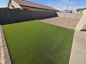 A green artificial turf in the foreground with a residential area in the background.