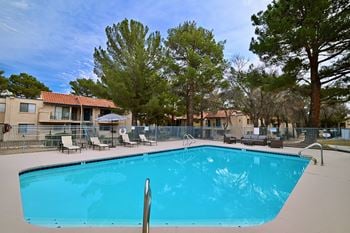 A swimming pool surrounded by trees and chairs.