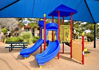 A playground with a blue slide and a red and yellow structure.