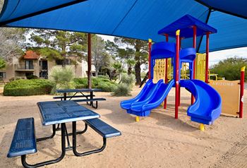 A playground with a blue slide and a picnic table.