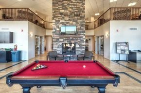 Castle Rock apartment for rent - A pool table is in the middle of a room with a stone wall and a TV.