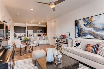 Castle Rock apartment for rent - A modern living room with a white sofa, a dining table with chairs, and a ceiling fan.