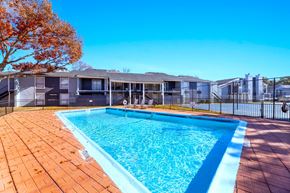 Wichita Falls apartment for rent - A swimming pool surrounded by a fence and trees.