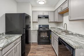 Wichita Falls apartment for rent - a kitchen with white cabinets and black appliances and granite counter tops