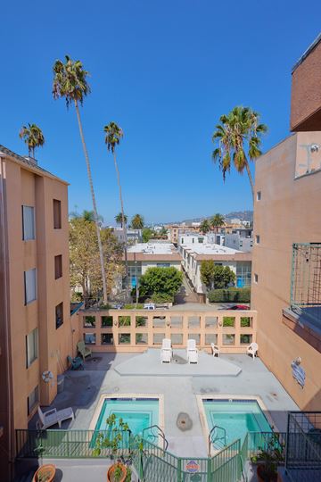 Los Angeles apartment for rent - A pool surrounded by a fence and palm trees.