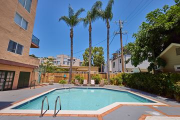 Los Angeles apartment for rent - A swimming pool surrounded by palm trees and residential buildings.