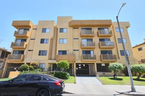 Los Angeles apartment for rent - A black car is parked in front of a tan building.